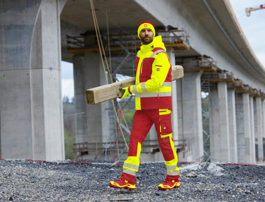 Warnschutz-Kleidung e.s.motion 24/7 von Engelbert Strauss. Warngelb mit Rot. Ein Herr auf der Baustelle.