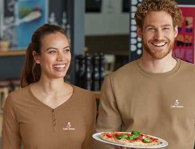 Eine Dame und ein Herr mit einem Shirt mit einem Stick-Branding von Engelbert Strauss. Zu sehen ist eine Kaffeetasse und „Café Simon“. 