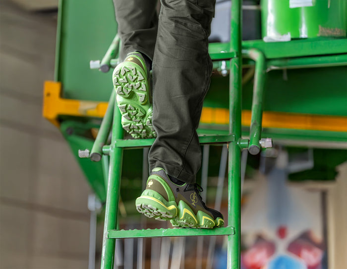 Ein Handwerker in den Sicherheitsschuhen e.s. Peoira steigt eine Metallleiter nach oben.