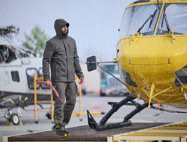 Mann trägt die STRAUSS 3 in 1 Funktionsjacke e.s.line.core bei Regen –rechts ist ein Hubschrauber. 