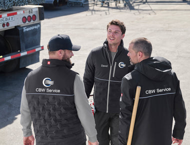 Drei Personen tragen Jacken und Westen mit gut sichtbaren Logos – als Beispiel für das Personalisieren von Workwear.